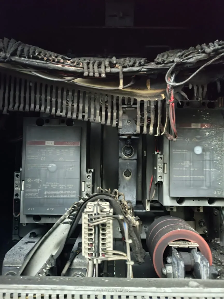 Upper section of a fire-damaged 1 MW central solar inverter showing AC output
cables with all insulation burned away and bare conductors hanging down from their
original cable tray position, two contactors below with heat-damaged
terminal connections, terminal block assembly in the lower center