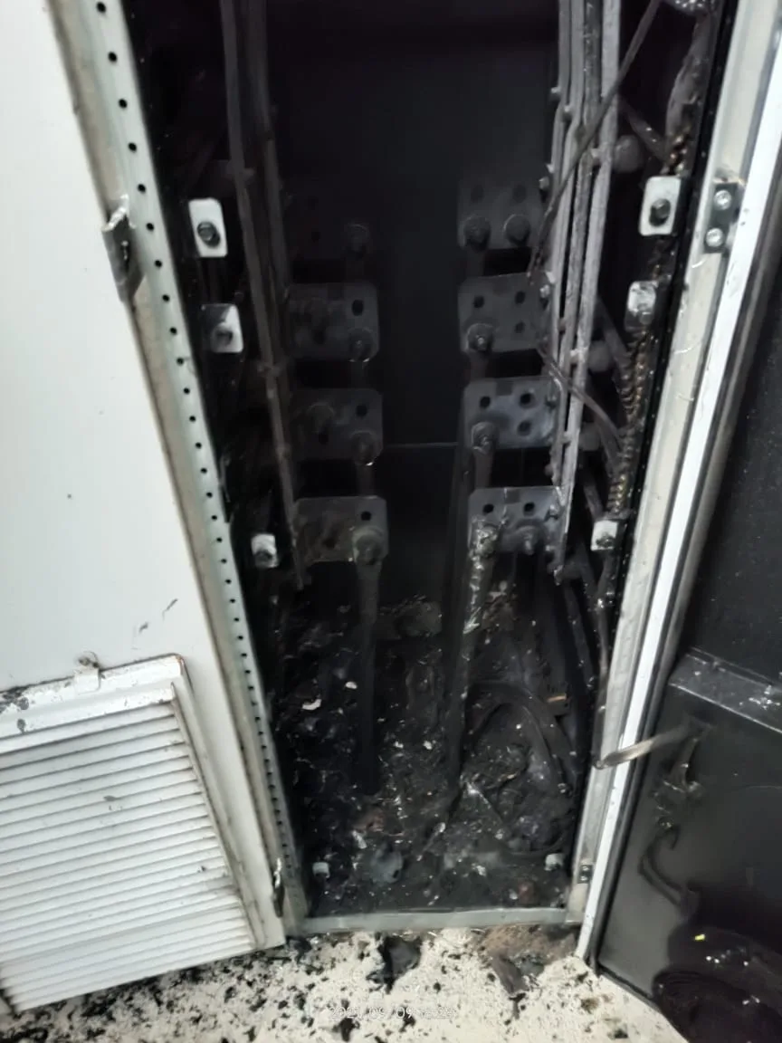 Full interior of a fire-damaged 1 MW central solar inverter with the door open,
all internal cables burned with no insulation remaining, ash and burned material
covering the cabinet floor, air inlet vent on the door panel undamaged, confirming
the fire started inside the cabinet