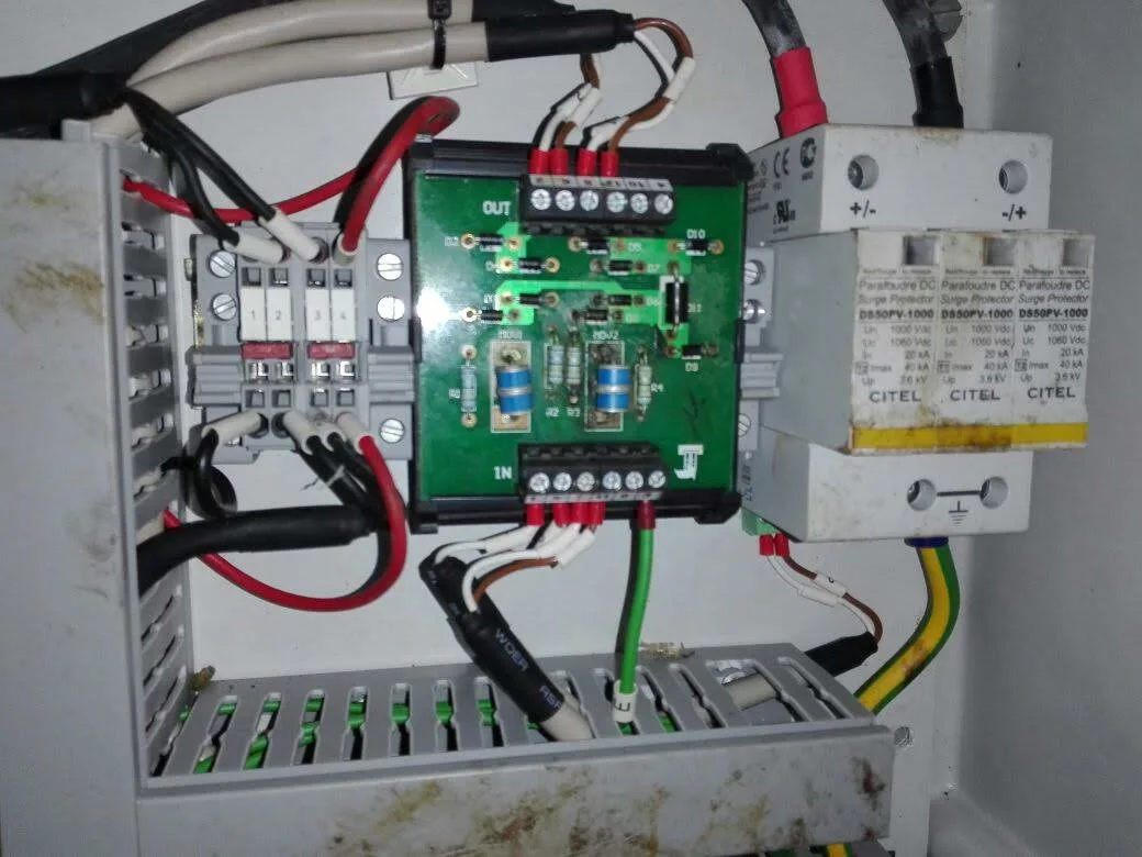 DC Surge Protector model DS50PV-1000 three-module assembly in yellow housing installed in inverter or string combiner box panel, Un 1000Vdc Uc 1060Vdc In 20kA T2 Imax 40kA Up 3.6kV, monitoring PCB board visible on left side of enclosure
