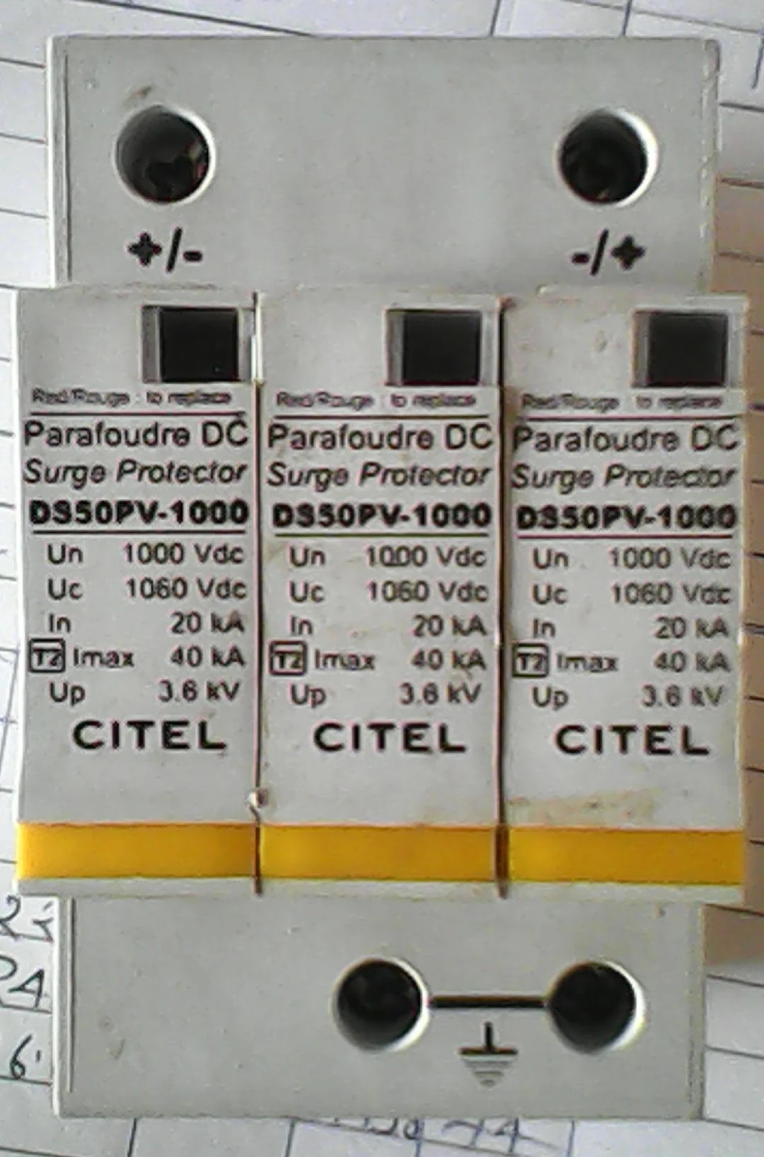 Close-up of three DC Surge Protector modules model DS50PV-1000 showing nameplate Un 1000Vdc Uc 1060Vdc In 20kA T2 Imax 40kA Up 3.6kV, status indicator windows on each module, positive and negative terminal markings