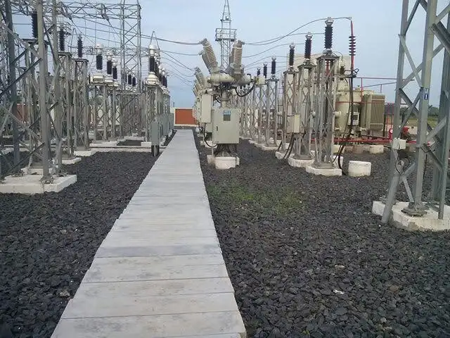 Wide view of a utility-scale solar plant evacuation substation showing power transformers, surge arresters on multiple HV bus structure frames, overhead conductors, and a concrete access walkway