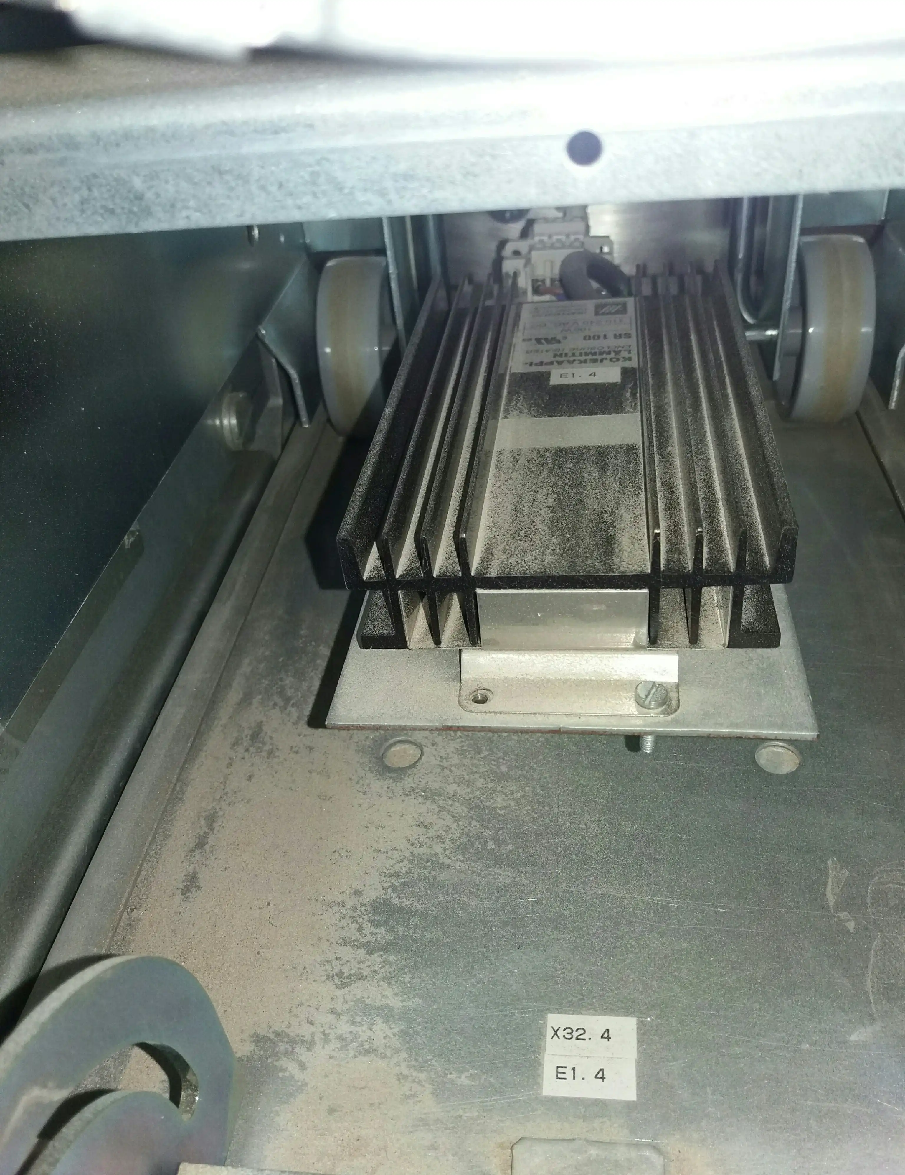 Close-up of finned component assembly inside a utility-scale central solar inverter bay, showing dust accumulation on aluminium fins and surrounding metal floor, typical of operating conditions in a utility-scale solar plant