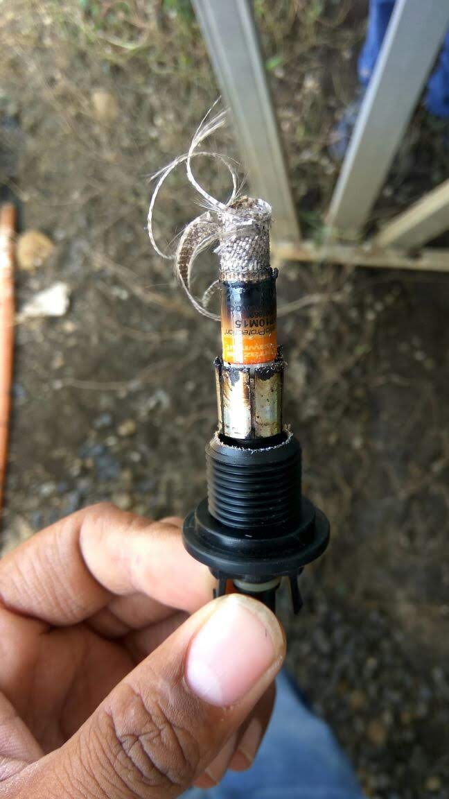 Close-up of a failed and thermally damaged MC4 solar PV connector held in hand, showing melted insulation, burned copper conductor, and frayed wire strands caused by high resistance at the crimp termination