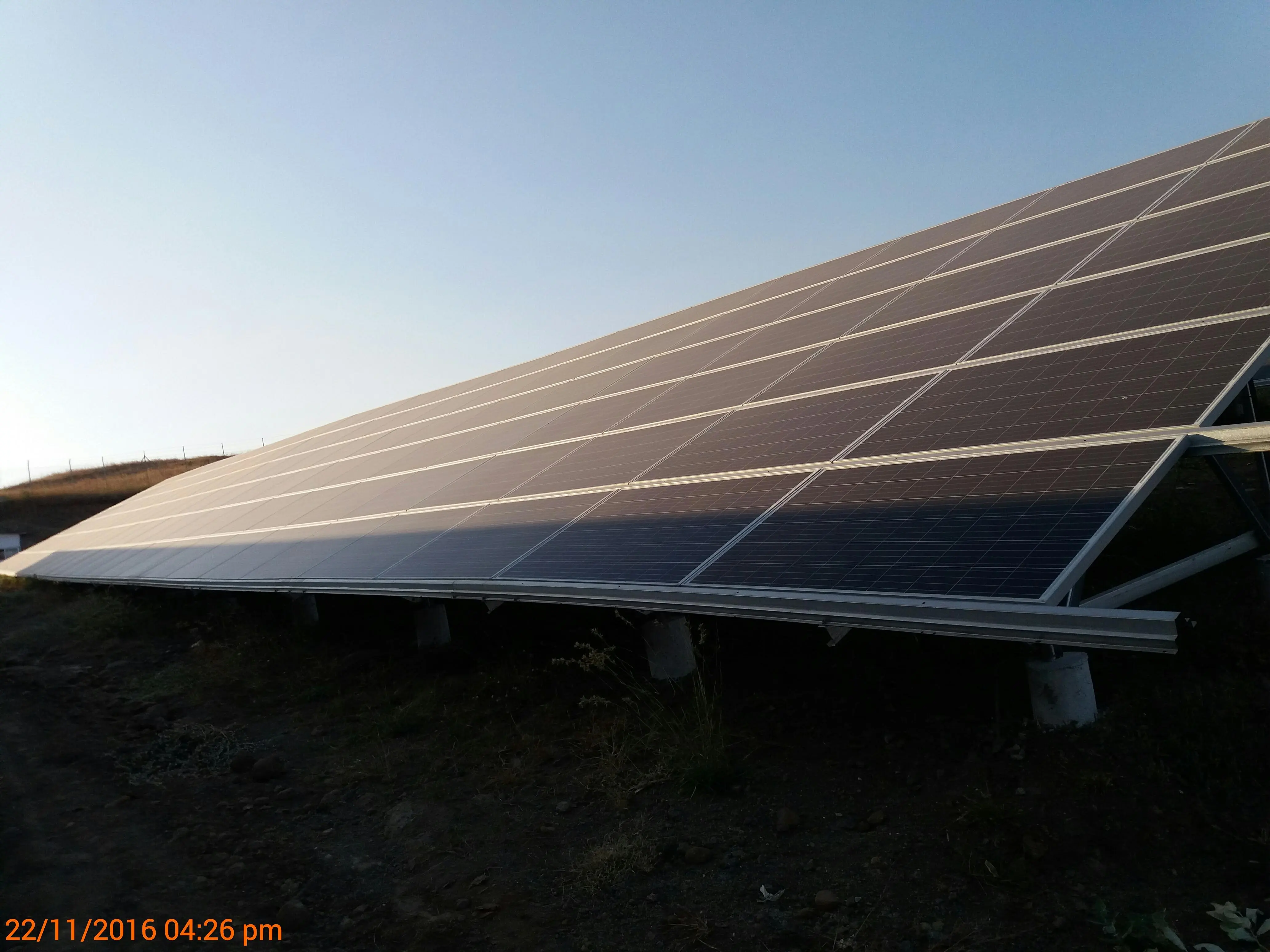 Inter-row shading on a ground-mounted solar PV array showing a sharp shadow line across the bottom cell rows of modules at 4:26 PM on 22 November 2016