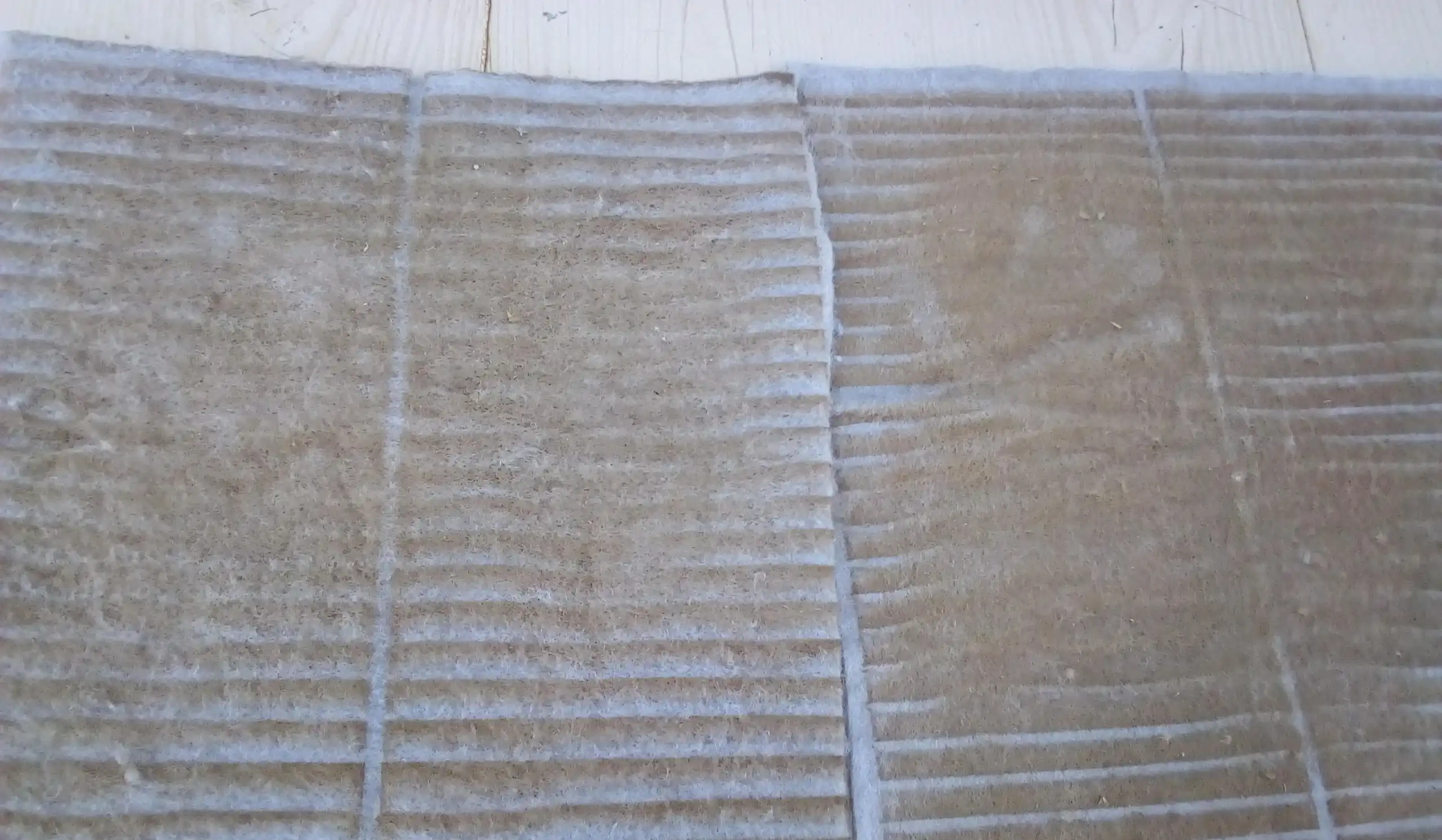 Heavily dust-loaded air intake filter mat removed from a utility-scale central solar inverter showing thick particulate accumulation across the entire corrugated filter surface significantly restricting cooling airflow