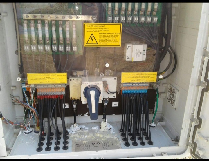 Interior of a solar string combiner box showing DC string fuses, terminal blocks, and rotary DC isolator switch